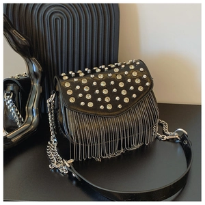 Macro detail of black leather crossbody bag with silver studs and metal chain fringe