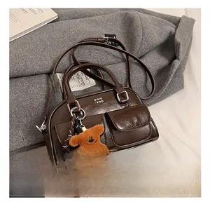 Détail du sac bowling en cuir ciré marron foncé avec logo et breloque ours en peluche