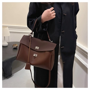 Detail of dark brown leather handbag with silver rotary lock shown on model