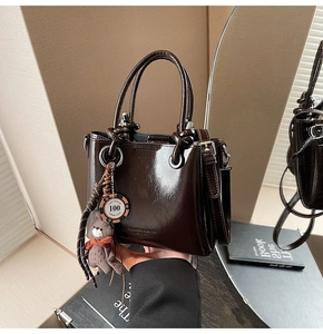 Détail du sac à main en cuir ciré marron foncé brillant avec breloque ours et étiquette