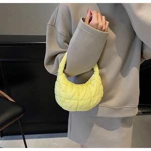 Close-up of a pale yellow quilted hobo bag with cloud texture on a model shoulder