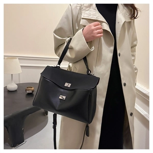 Close-up of black matte leather handbag with silver turn-lock and adjustable shoulder strap