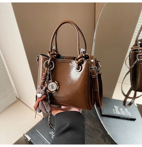 Détail du sac seau en cuir marron huilé avec breloque ours et logo embossé
