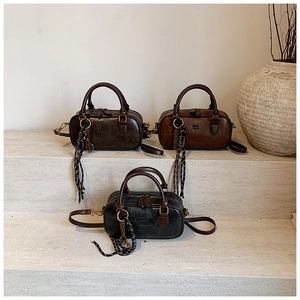 Three vintage Boston bags in black, grey and brown displayed on stone stairs with silk scarf