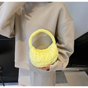 Macro detail of bright yellow quilted cloud bag with padded nylon texture and metal zipper
