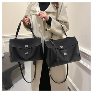 Detail of classic black leather handbag with silver turn-lock closures and adjustable strap