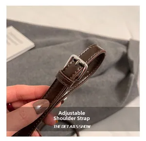 Détail de la bandoulière réglable en cuir marron foncé avec boucle argentée polie