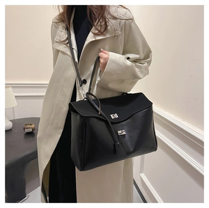 Chic black PU leather tote handbag with silver twist lock shown on a modern side table