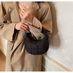 Detail view of black quilted crescent handbag showing fluffy down texture and chic design