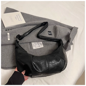 Detail view of high-quality pleated black faux leather shoulder bag with wide strap design
