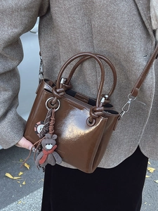 Sac seau marron en cuir huilé brillant avec breloque ours et bandoulière réglable