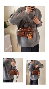 Détail d'un sac bowling vintage marron avec poches latérales et breloque ours décorative