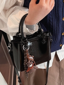 Sac seau classique en cuir verni noir avec poignée nouée marron et pendentif ours