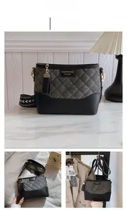Detail of black quilted shoulder bag featuring grey suede patchwork and woven strap
