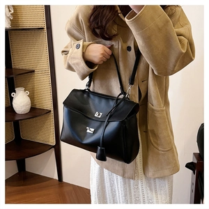 Detail of a black leather handbag with silver metal twist locks and a shoulder strap