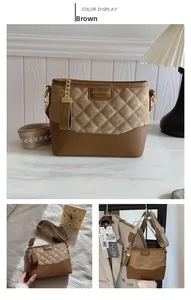 Detail of a brown quilted crossbody bucket bag with gold hardware and chain charm