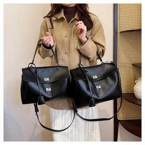 Detail of elegant black trapezoid handbag featuring silver twist lock and smooth texture