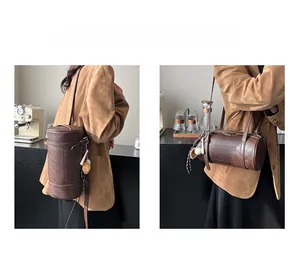 Dual-way carry demonstration of vintage brown leather cylinder bag in a cozy cafe setting