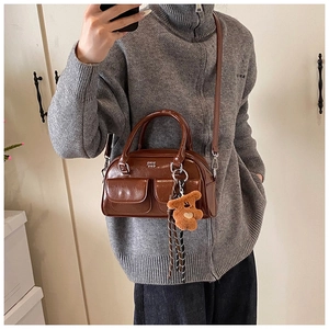 Détail d'un sac bowling en cuir marron brillant avec poches et breloque ourson