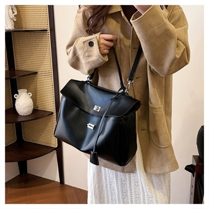 Detailed view of large black leather shoulder bag with silver turn-lock for business commuting