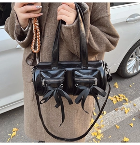 Gros plan d'un sac à main noir brillant style ballet avec nœuds et détails argentés