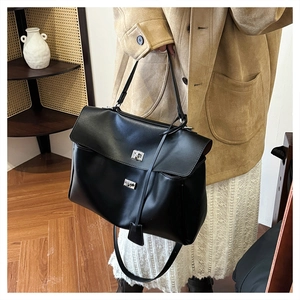 Side view of a large black matte leather tote bag with silver turn-lock and shoulder strap
