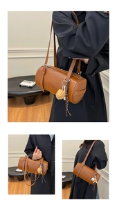 Detail view of brown leather cylinder bag with embossed letters and cute bag charm