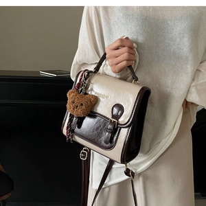 Close-up of vintage contrasting PU leather handbag with decorative plush bear charm