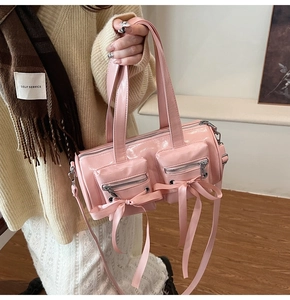 Gros plan du sac cylindre en cuir verni rose avec nœuds décoratifs en ruban balletcore