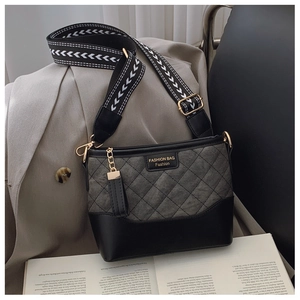 Detail of grey diamond-quilted bucket bag with contrast trim and patterned wide strap