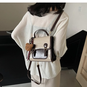Retro cream and brown crossbody bag with bear pendant worn by a model from behind