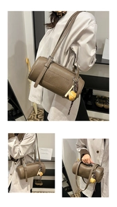 Detailed view of brown leather cylinder bag featuring embossed letters and strawberry charm