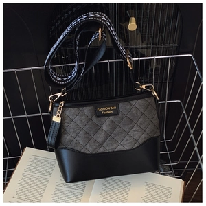 Detail of quilted bucket bag with geometric wide strap and fashion plaque in a metal basket
