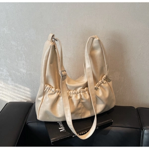 Detailansicht der beigen Kunstlederfalten und des doppelten Gurtmodells dieser Tasche
