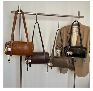 Detailed view of matte leather barrel bags in four colors with baseball charms on hangers