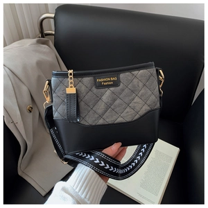 Detail of grey quilted crossbody bag with black leather base and stylish woven strap