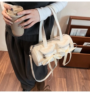 Détails d'un sac cylindre crème chic avec des nœuds décoratifs et des poches avant
