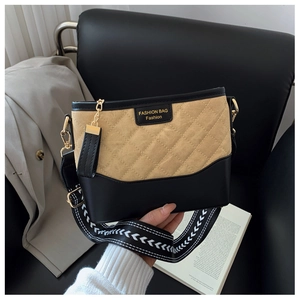 Detail of quilted beige and black leather bucket bag with arrow patterned strap