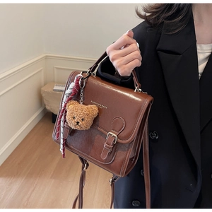 Brown vintage square handbag with cute bear charm and fashion text details on black suit