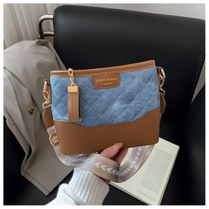 Close-up of diamond quilted denim bucket bag with brown leather trim and woven strap