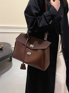 Brown leather handbag with silver metallic buckle and adjustable strap shown on model