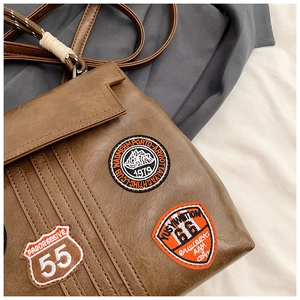 Close-up of vintage brown leather backpack with detailed embroidery patches and stitching
