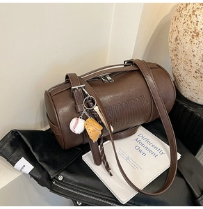 Close-up of retro brown cylinder bag with HADOUDOU embossing and baseball charm