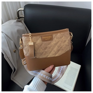 Close-up of brown leather and beige quilted bucket bag with a wide woven shoulder strap