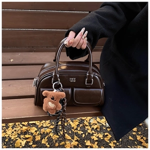 Détail du sac bowling rétro marron foncé avec fini brillant et charm d'ours en peluche