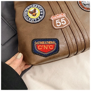 Detail of brown litchi pattern leather backpack with vintage embroidery patches