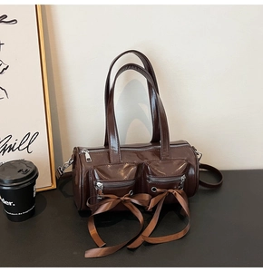 Détail du sac tonneau en PU marron brillant avec rubans et doubles poches zippées avant
