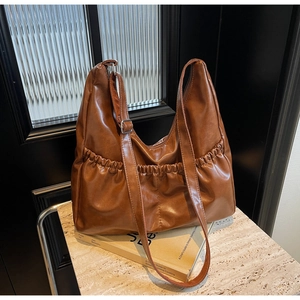 Detail einer dunkelbraunen Ledertasche mit einzigartigen gefalteten Vordertaschen