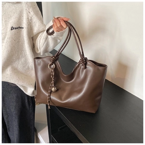 Detail view of coffee brown tote bag featuring wavy edges and stylish knot handles