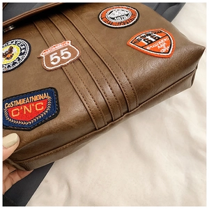 Detail of coffee brown PU leather backpack with vintage embroidery patches and stitching